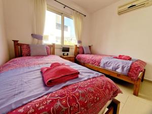 a bedroom with two beds with red sheets and a window at C5 Vanessa Poolside Apartment in Peyia +11 photos