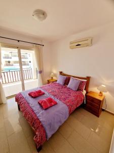 a bedroom with a bed with two red pillows on it at C5 Vanessa Poolside Apartment in Peyia
