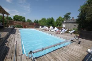 a swimming pool on a deck with chairs and a house at chambre zen in Condé-sur-Noireau