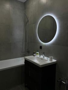 ein Badezimmer mit einem Waschbecken, einem Spiegel und einer Badewanne in der Unterkunft Комфорт in Oral