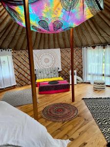 um quarto com uma tenda com uma cama e piso em madeira em Spa Les Jardins De Chiron Lodges et Tiny House dans le sud em Sauve