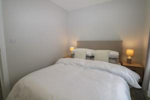 1 dormitorio con 1 cama blanca y 2 almohadas en The Secret Cottage 4A, en Seaford