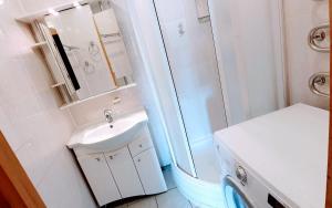 bagno bianco con lavandino e doccia di Apartments in the Sun CITY a Šiauliai