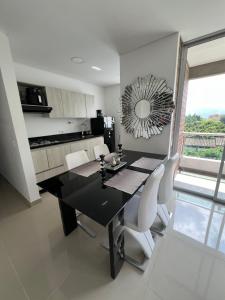 uma sala de jantar com uma mesa preta e cadeiras brancas em Luxor apartamentos em Medellín