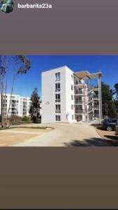 a white building in front of a parking lot at Hermoso Departamento El Tabo in El Tabo