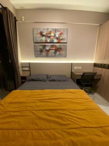 Cilenggangにあるapartemen sky house bsdのベッドルーム1室(黄色のベッド1台付)が備わります。壁には絵画2点が飾られています。
