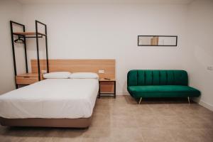 een slaapkamer met een bed en een groene bank bij Polorooms in Zaratán