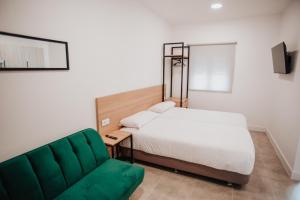a bedroom with a bed and a green couch at Polorooms in Zaratán