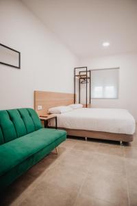 1 dormitorio con 2 camas y 1 sofá verde en Polorooms en Zaratán