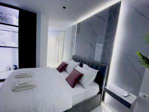 a bedroom with a white bed with purple pillows at Suncity Tirana Luxury Apartments (Ap. 01) in Tirana