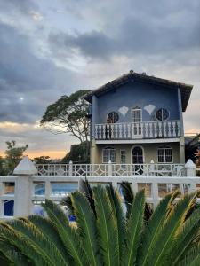 una casa azul con una valla blanca y palmeras en Lugar de Ser Feliz Casa da Jô, en Saquarema