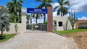 a hotel sign in front of a building with palm trees at Hotel Aconchego do Velho Chico in Piranhas
