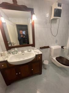 un homme prenant une photo d'une salle de bains avec lavabo dans l'établissement Panoramic Orselina, à Orselina