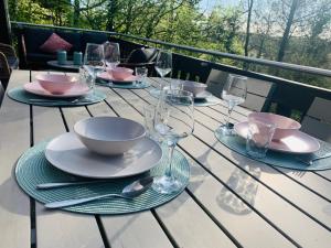- une table avec des assiettes et des verres à vin sur un balcon dans l'établissement Heerlijk vakantiehuis in bos bij Durbuy, à Durbuy