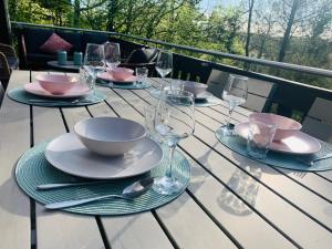 a table with plates and wine glasses on a balcony at Heerlijk vakantiehuis in bos bij Durbuy in Durbuy