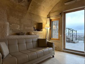 a living room with a couch and a large window at Kistar Cave Hotel in Uçhisar