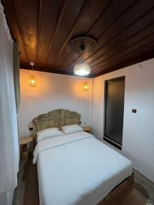 um quarto com uma cama branca e uma cadeira em Albayrak Konağı Otel em Amasya
