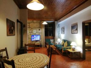 uma sala de estar com uma mesa e um sofá em Casa da Ponte em Alvoco da Serra