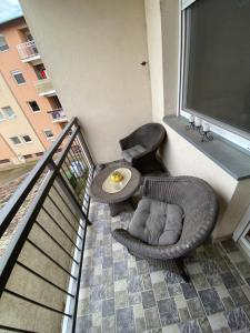 a balcony with two wicker chairs and a table at SKY2 APARTMAN in Subotica
