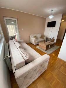 a living room with a white couch and a tv at SKY2 APARTMAN in Subotica