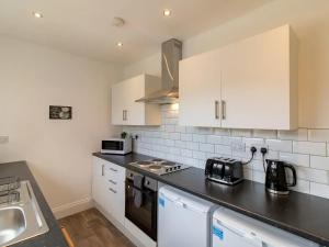 a kitchen with white cabinets and a black counter top at Pass the Keys Fabulous location stylish home in Spennymoor