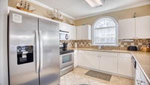 a kitchen with white cabinets and a stainless steel refrigerator at 421 Cypress Bend condo in North Myrtle Beach