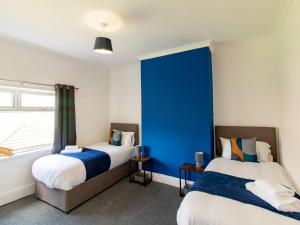 two beds in a room with a blue wall at Pass the Keys Fabulous location stylish home in Spennymoor