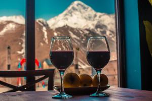 two glasses of wine sitting on a table in front of a window at Chemodann Kazbegi in Stepantsminda