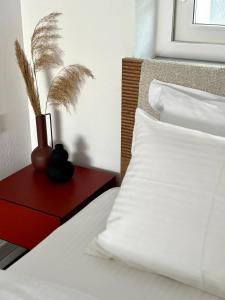 uma cama com lençóis brancos e um vaso numa mesa vermelha em MYROVOLOS APARTMENTS em Quios