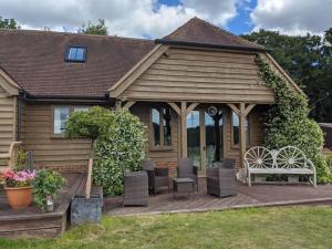 una casa con una terraza de madera con sillas y un banco en The Barn New Forest Free Paddle boarding & free Zip wire., en Ringwood