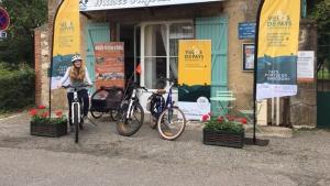 a woman standing next to two bikes in front of a store at Gîte Ensemont in Saramon