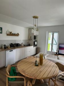 ein Wohnzimmer mit einem Holztisch und einer Küche in der Unterkunft Le coin des hirondelles in Asfeld