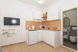 cocina con armarios blancos, lavabo y espejo en Apartments Lovrić, en Vodice