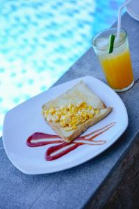 ペニダ島にあるDESILA Beach Houseの白皿(サンドイッチ付)とオレンジジュース