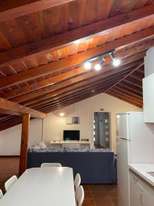 a kitchen with wooden ceilings and a table and a refrigerator at Santo Cristo Loft in Lajes das Flores