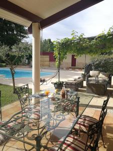 une terrasse avec une table, des chaises et une piscine dans l'établissement Au Doux Repos, à Lucbardez-et-Bargues