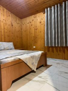 1 dormitorio con 1 cama y pared de madera en Aral guesthouse, en Borsh