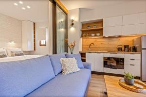 Una sala de estar con un sofá azul y una cocina. en Lola Apartments, en Liapades