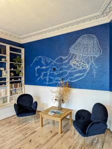 una habitación con 2 sillas y una pared con un dibujo en The Chesterfield Guest House, Torquay, en Torquay