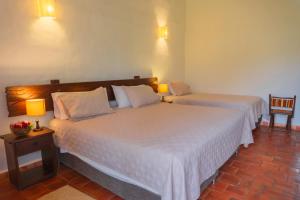 Dos camas en una habitación de hotel con dos lámparas. en Hotel Hacienda Macedonia, en Barichara