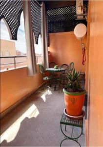 einen Balkon mit einem Tisch und einer Pflanze in einem Topf in der Unterkunft Atla's Ruby in Marrakesch