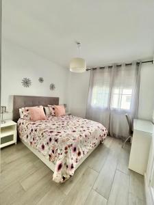 een witte slaapkamer met een groot bed met roze kussens bij Tulipanes Benalmádena - Parking privado in Benalmádena