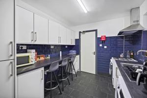 eine Küche mit weißen Schränken und blauen Fliesen in der Unterkunft Stunning 5 bedroom home families HS2 NEC Airport contactors welcome in Birmingham