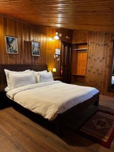 a bedroom with a large bed with wooden walls at Hotel Mangalemi in Berat