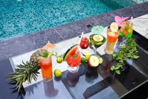 a glass table with cocktails and fruit on it next to a swimming pool at The Autograph Inn in Siliguri