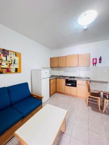 a living room with a blue couch and a kitchen at Garden View Apartment No 40 in Tal-Franċiż