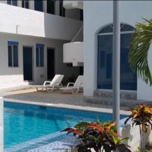 a swimming pool with two chairs and a building at Moderno departamento vacacional. in Tonsupa