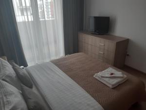 sypialnia z łóżkiem i telewizorem na komodzie w obiekcie Apartament Marcel - Coresi Mall w Braszowie