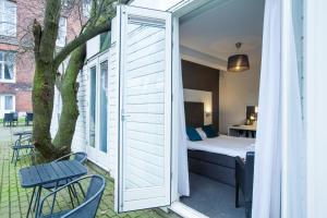 a room with a bed and a window and a tree at Hotel Vossius Vondelpark in Amsterdam