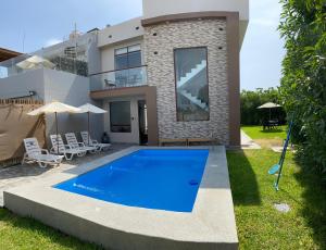 a villa with a swimming pool in front of a house at ENCANTADORA Casa de Campo - Ica in Ica